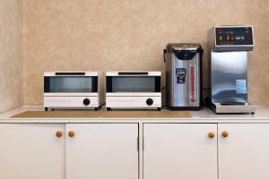 a counter with three microwaves and a coffee machine at Tabist Daibou Ichihara Mens Only in Ichihara