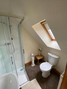 a bathroom with a toilet and a glass shower at Cleadale flat in Breakish