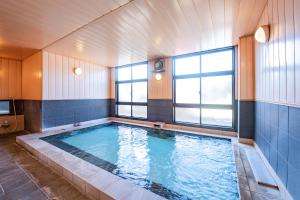 a large swimming pool in a room with windows at Tabist Daibou Ichihara Mens Only in Ichihara
