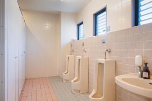 a bathroom with a row of urinals and a sink at Tabist Daibou Ichihara Mens Only in Ichihara