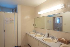 a bathroom with three sinks and a large mirror at Tabist Daibou Ichihara Mens Only in Ichihara