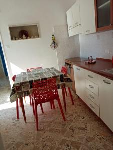 a kitchen with a table and two red chairs at Appartamento vacanze Piazza del Popolo in Marsala