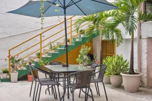 a table and chairs with a blue umbrella and stairs at Botánica Casa Hotel in Medellín