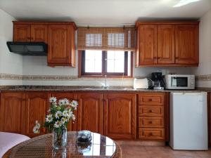 a kitchen with wooden cabinets and a table with flowers at El Somadero B in Fuencaliente de la Palma