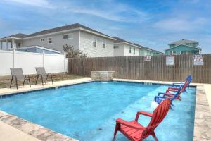 a swimming pool with two lawn chairs in a yard at Shorts Story in Port Aransas