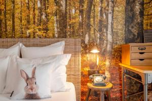a bedroom with a rabbit on the bed with a forest mural at La Maison Hôtel Mulhouse Centre in Mulhouse