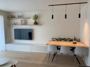 a dining room with a table and a tv on a wall at Pluk de dag in Oostduinkerke