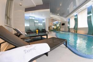 a pool in a hotel with chairs and a table at Taurus Hotel & SPA in Lviv