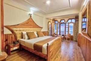 a bedroom with a large bed with a wooden headboard at Hotel Ibex in Manāli