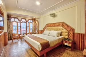 a bedroom with a large bed and a table at Hotel Ibex in Manāli