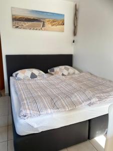 Bett in einem Zimmer mit einem Bild an der Wand in der Unterkunft Strandstern Norddeich in Norddeich