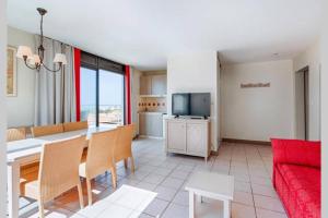 een woonkamer met een tafel en een rode bank bij T4 Vue exceptionnelle sur le Golf du Lion in Cap d'Agde