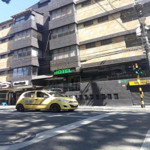 um táxi amarelo estacionado em frente a um edifício em Hotel Ruiseñor Itagui em Itagüí