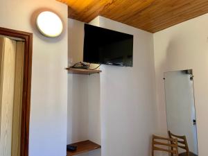 uma sala de estar com televisão numa parede branca em Le Pidanoux em Saint-Julien-du-Verdon