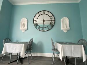 a dining room with two tables and a clock on the wall at Belvedere - Adults Only in Blackpool