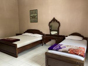 a bedroom with two beds with a mirror and a dresser at Hotel Garuda Syariah near Alun Alun Banjarnegara in Wonosobo +46 photos