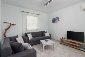 a living room with a couch and a tv at Zanart maisonette II in Tripití
