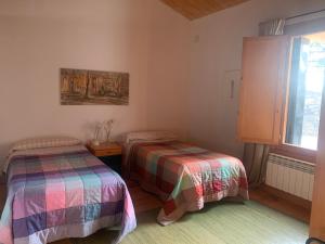 a bedroom with two beds and a window at casa rural de un artista en plena naturaleza piscina y parque de esculturas en villarcayo in Villarcayo
