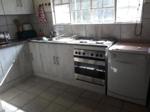 a white kitchen with a stove and a sink at African Sky in Marloth Park