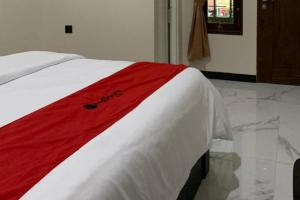 a bed with a red and white blanket on it at RedDoorz Syariah near Kawasan Simpang Lima Pati in Pati