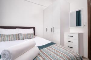 a white bedroom with a bed and a dresser at Sayan Apart Hotel in Kemer