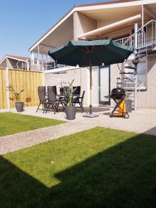 a grill with a green umbrella next to a house at Ostreahof Gezin & Familie vakantiehuis aan strand en jachthaven in Kamperland