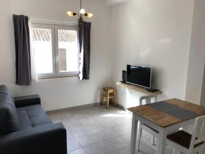 sala de estar con sofá, TV y mesa en Casa do Viajante - Suite en Zambujeira do Mar