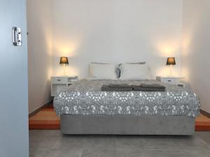 a bedroom with a bed with two lamps on two tables at Casa do Viajante - Suite in Zambujeira do Mar
