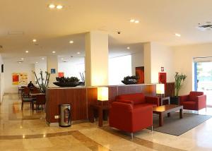 a waiting room with red chairs and a bar at One Ciudad del Carmen Concordia in Ciudad del Carmen