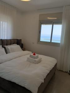 a bedroom with a large white bed with a window at sea view in ‘Akko