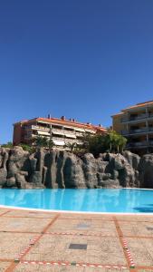 una piscina de agua azul frente a un edificio en Piso Jardines del Teide en el Puerto de la Cruz en Puerto de la Cruz