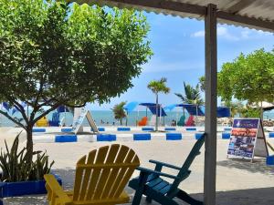 two chairs sitting on a beach with the ocean in the background at Hotel Don Toño Tolú in Tolú
