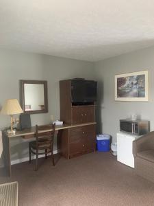 a room with a desk with a television and a chair at Hilltop Motel & Restaurant in Grand Falls