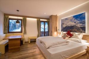 a bedroom with a bed and a desk and two windows at B&B La Tambra - central with Restaurant in Santa Cristina in Val Gardena