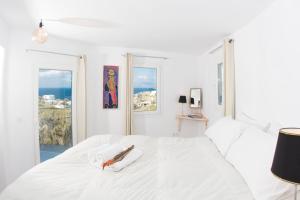 a white bedroom with a white bed with a window at Lilly's Home -2 Bedrooms in Mýkonos City