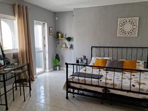 Schlafzimmer mit einem Bett, einem Tisch und einem Fenster in der Unterkunft Deluxe B&B "Casa Alegria", Tarrafal in Tarrafal