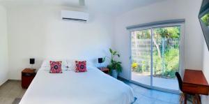 Un dormitorio blanco con una cama grande y una ventana. en Aqua Guesthouse, en Puerto Morelos 59 fotos más