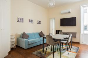 ein Wohnzimmer mit einem blauen Sofa und einem Tisch und Stühlen in der Unterkunft Anna's Luxury Apartment in Palermo