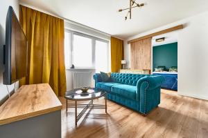 a living room with a blue couch and a table at Apartament Księżycowy in Olsztyn