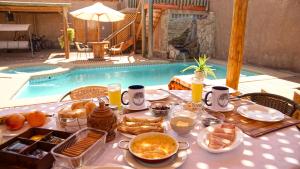 - une table avec de la nourriture pour le petit-déjeuner à côté de la piscine dans l'établissement La Casa de José, à San Pedro de Atacama