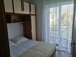 ein Schlafzimmer mit einem Bett und einem großen Fenster in der Unterkunft Apartments Petrica in Malinska
