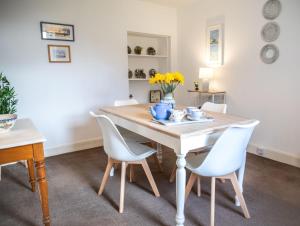 a dining room with a wooden table and white chairs at Mill Cottage in Forres