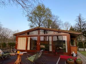 uma pequena cabina com portas de vidro e uma mesa e cadeiras em Chalet de kleine Eekhoorn em Lage Mierde