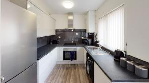 una cocina con armarios blancos y encimeras negras en Marina House, en Hull