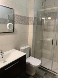 a bathroom with a toilet and a glass shower at Apartamento la Ribera in Suances +29 photos