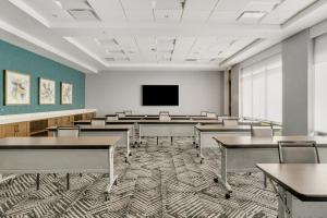 an empty classroom with tables and a tv at The Forester, a Hyatt Place Hotel in Lake Forest