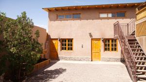 uma casa de tijolos com portas de madeira e uma escada em La Casa de José em San Pedro de Atacama