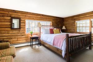 Schlafzimmer mit Holzwänden, einem Bett und einem Spiegel in der Unterkunft Kedron Valley Inn in Woodstock