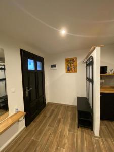 um quarto vazio com uma porta preta e pisos de madeira em Apartmán Ginko I em Koliba