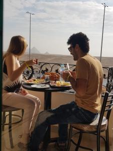 
a man and a woman sitting at a table at Pyramids Planet Hotel in Cairo
